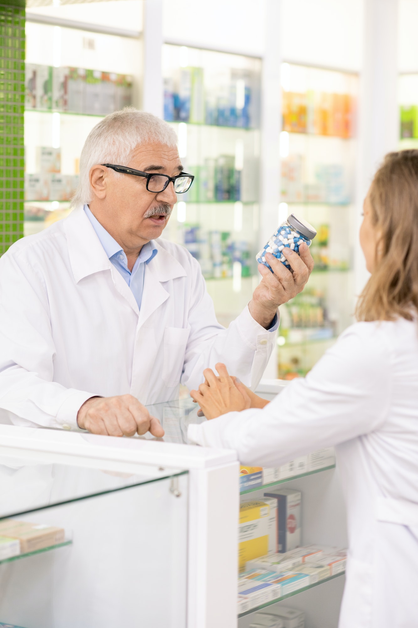 Inicio 8 senior owner of contemporary drugstore showing his subordinate jar with pills